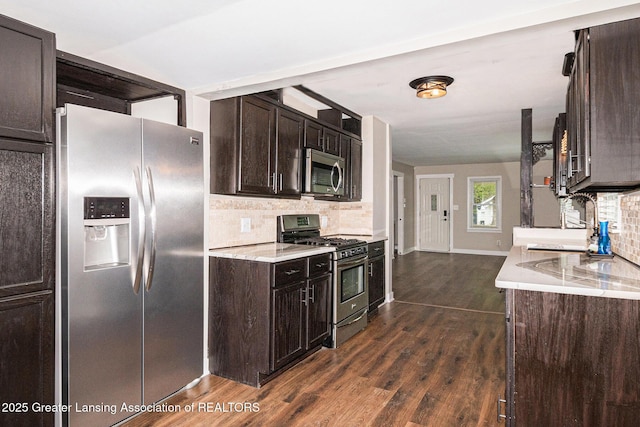 kitchen with dark brown cabinets, stainless steel appliances, tasteful backsplash, and dark wood finished floors