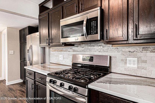 kitchen featuring backsplash, light stone counters, appliances with stainless steel finishes, and dark brown cabinetry