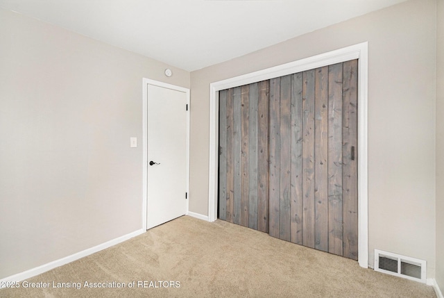 unfurnished bedroom featuring baseboards, a closet, visible vents, and carpet