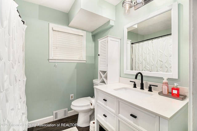 bathroom featuring toilet, baseboards, visible vents, vanity, and wood finished floors