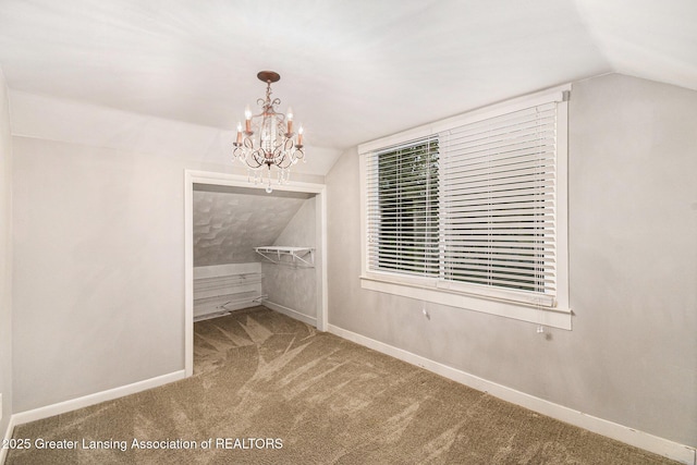 interior space featuring carpet, baseboards, lofted ceiling, and a notable chandelier