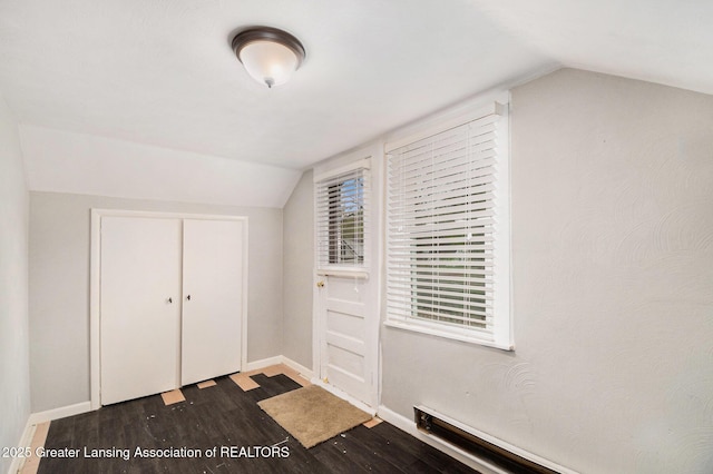 additional living space with dark wood-style flooring, lofted ceiling, and baseboards