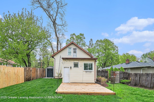 rear view of property with a deck, an outdoor structure, a storage shed, and a fenced backyard
