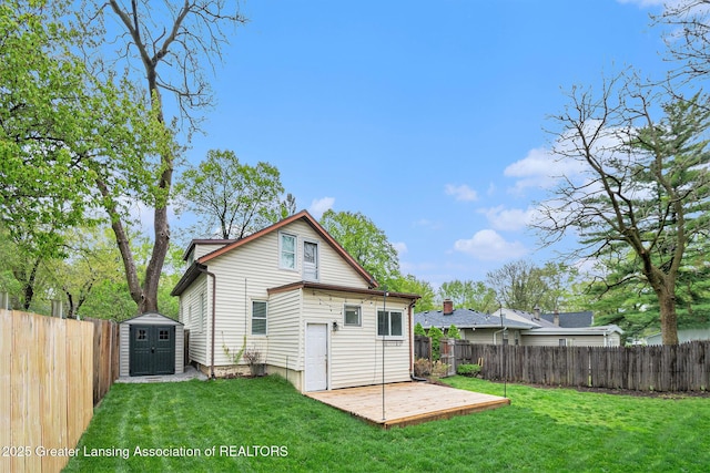 rear view of house with a lawn, a shed, and a fenced backyard