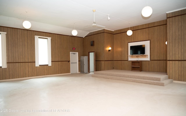 unfurnished living room with wooden walls and ceiling fan