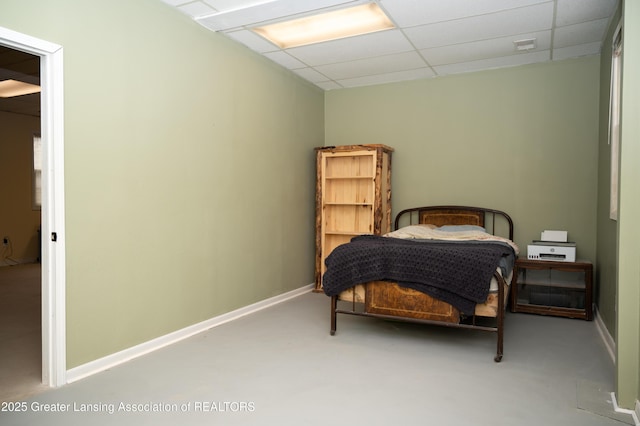 bedroom with a paneled ceiling and baseboards