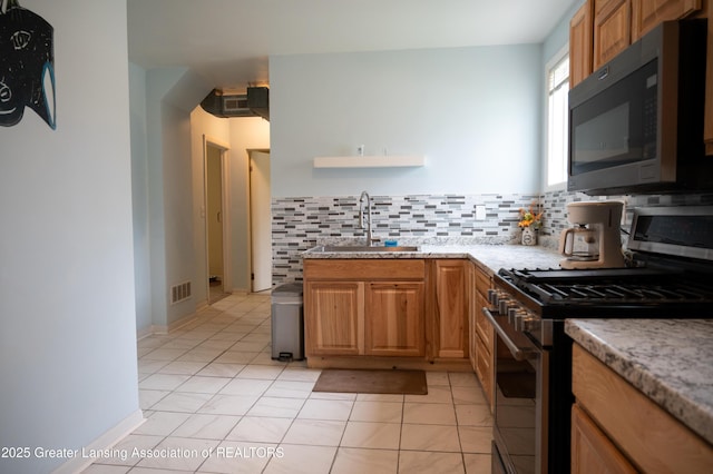 kitchen with stainless steel gas stove, a sink, open shelves, decorative backsplash, and light stone countertops