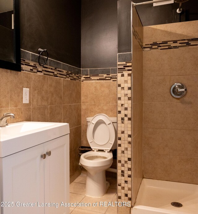 full bath featuring a shower stall, tile walls, toilet, tile patterned floors, and vanity