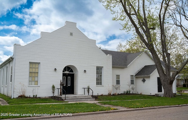 view of front facade featuring a front lawn and roof with shingles