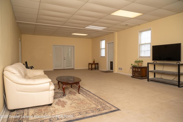 living area featuring a drop ceiling, carpet, and baseboards