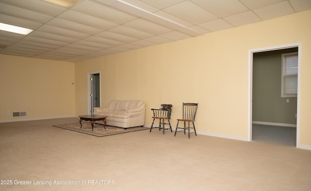 living area featuring a drop ceiling, carpet, and baseboards