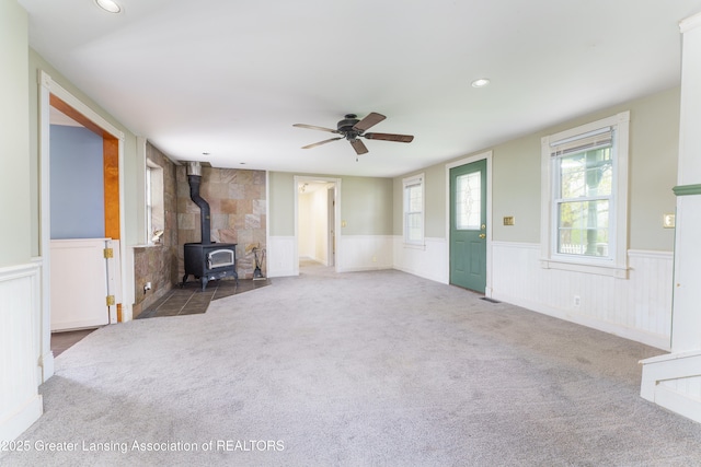 2820 N Lima Center Rd, Dexter, MI 48130 - unfurnished living room featuring a wood stove, a ceiling fan, wainscoting, and carpet floors