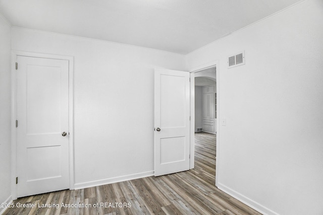 1124 Poxson Ave, Lansing, MI 48910 - unfurnished room featuring wood finished floors, arched walkways, ornamental molding, and baseboards