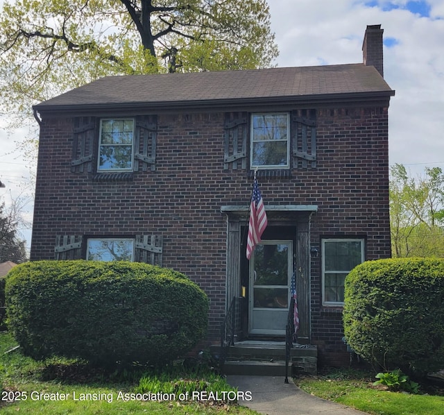 view of front of property featuring brick siding and a chimney