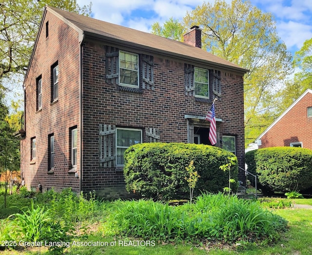 view of front facade featuring brick siding and a chimney