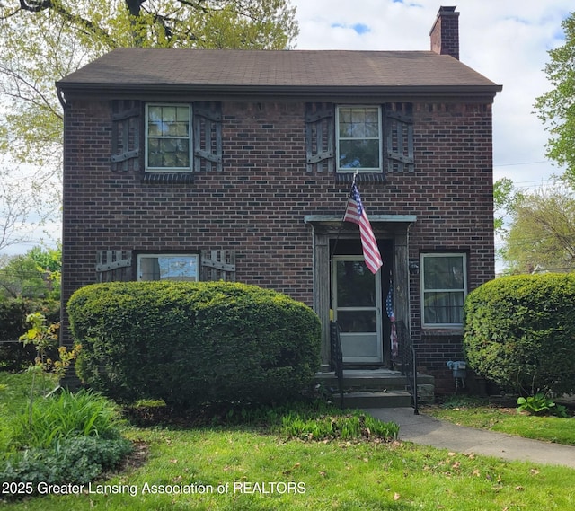 view of front of property featuring a chimney and brick siding