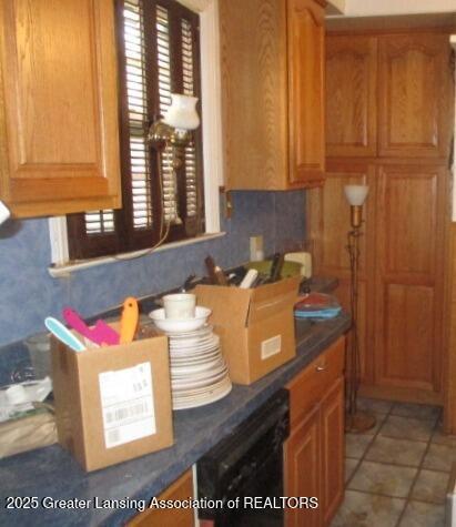 kitchen with black dishwasher, dark countertops, brown cabinetry, and backsplash