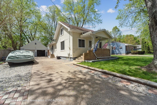 view of front of property featuring a detached garage, an outbuilding, and a front yard