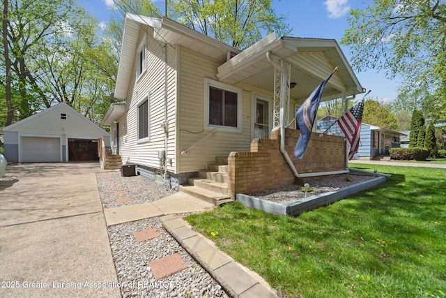 view of front of house with a detached garage, an outbuilding, and a front lawn