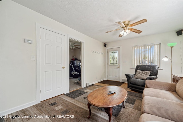 living room with a ceiling fan, baseboards, and wood finished floors