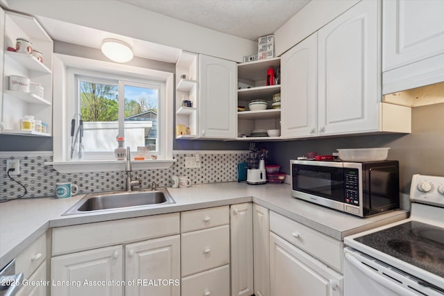 kitchen featuring electric stove, open shelves, stainless steel microwave, a sink, and white cabinets