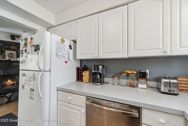 kitchen featuring dishwasher, freestanding refrigerator, white cabinetry, and light countertops
