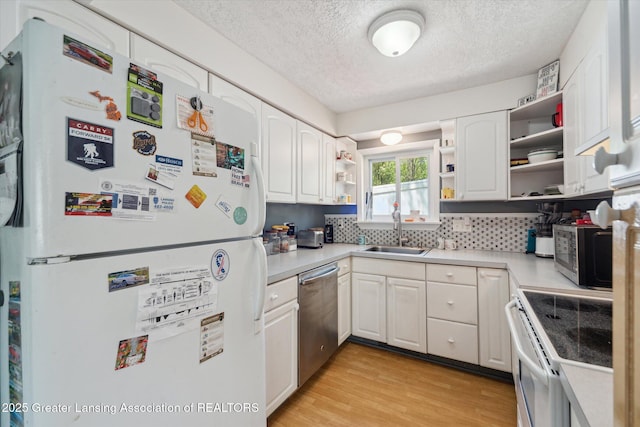 kitchen with stainless steel appliances, a sink, open shelves, a textured ceiling, and light wood-type flooring
