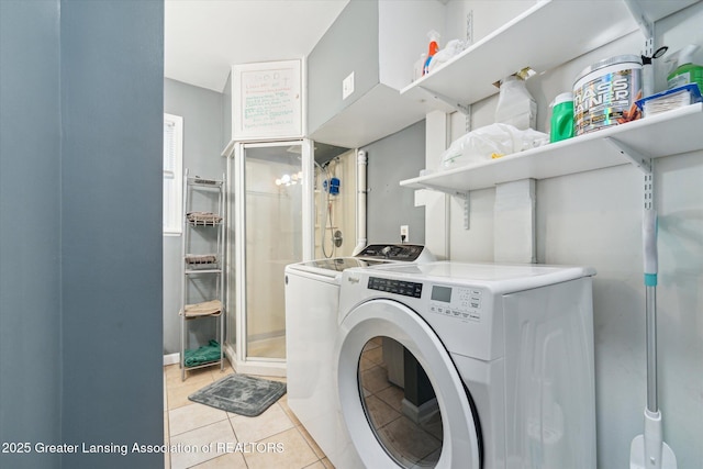 clothes washing area with washing machine and dryer and light tile patterned floors