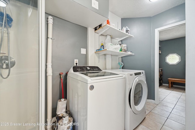laundry room featuring washer and dryer, light tile patterned floors, and a textured ceiling