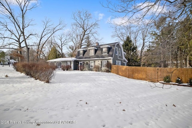 snow covered rear of property with fence and a chimney