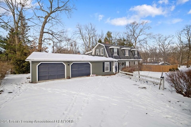 dutch colonial featuring a gambrel roof, fence, a chimney, and a garage