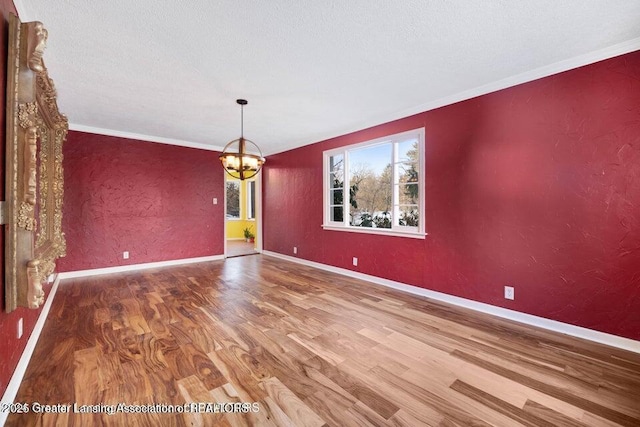 unfurnished dining area with wood finished floors, a chandelier, ornamental molding, and baseboards
