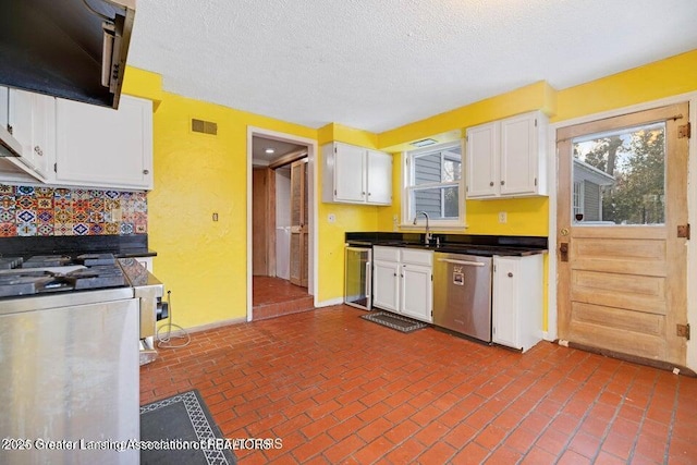 kitchen with stainless steel dishwasher, beverage cooler, white cabinetry, a sink, and dark countertops