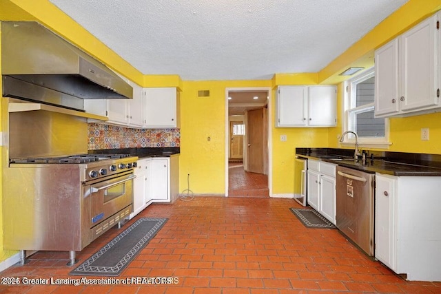 kitchen featuring stainless steel appliances, under cabinet range hood, a sink, dark countertops, and white cabinets