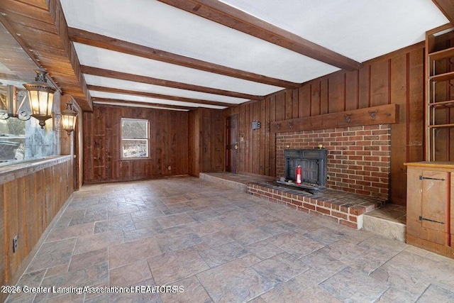 unfurnished living room featuring wood walls, stone tile floors, and beam ceiling