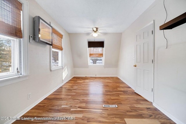 spare room with plenty of natural light, ceiling fan, wood finished floors, and baseboards