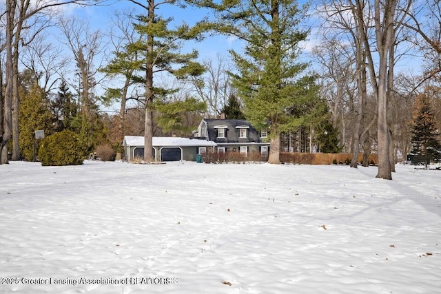 snowy yard featuring view of wooded area