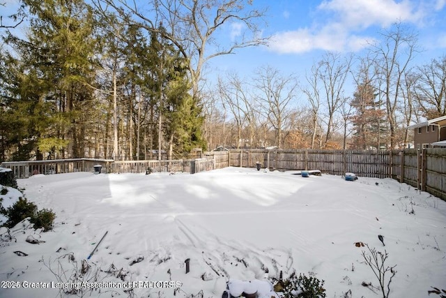 snowy yard with a fenced backyard