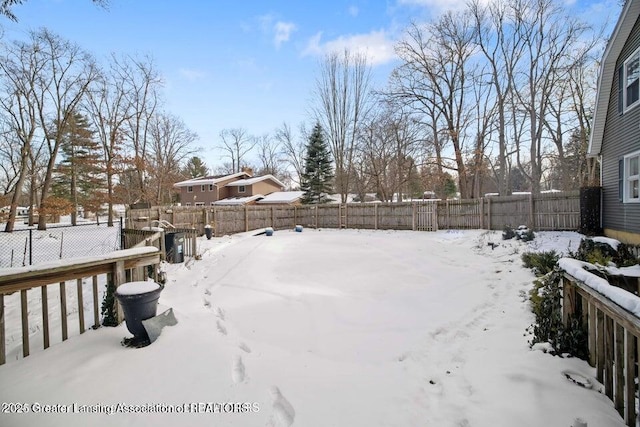 snowy yard with a fenced backyard