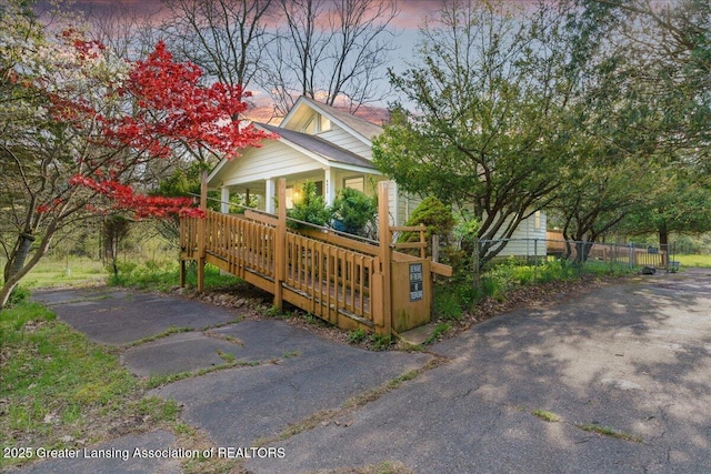 view of side of property featuring covered porch and fence
