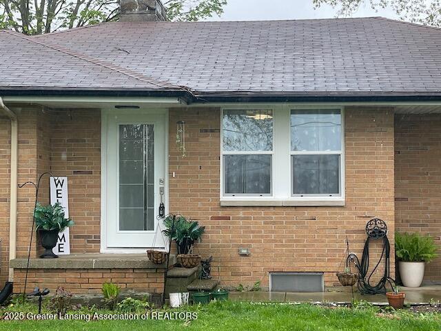 6422 E Saginaw Hwy, Grand Ledge, MI 48837 - entrance to property featuring brick siding, a chimney, and roof with shingles