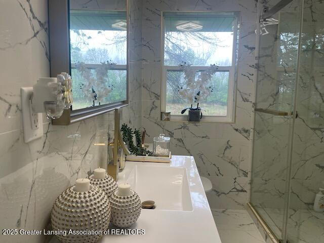 6422 E Saginaw Hwy, Grand Ledge, MI 48837 - bathroom featuring a marble finish shower, plenty of natural light, and marble tiled floors