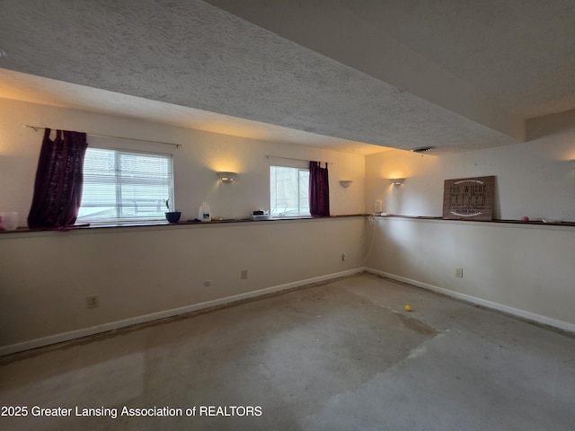 spare room with baseboards, a textured ceiling, and concrete floors