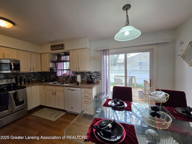 kitchen featuring appliances with stainless steel finishes, dark wood finished floors, backsplash, and a sink