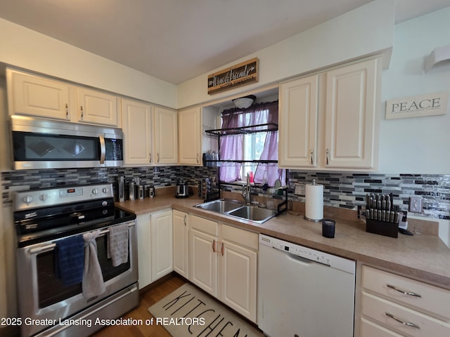 kitchen with stainless steel appliances, a sink, tasteful backsplash, white cabinets, and light countertops