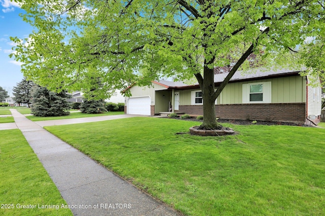 910 Pecos Dr, Lansing, MI 48917 - view of front of home featuring brick siding, concrete driveway, an attached garage, board and batten siding, and a front yard