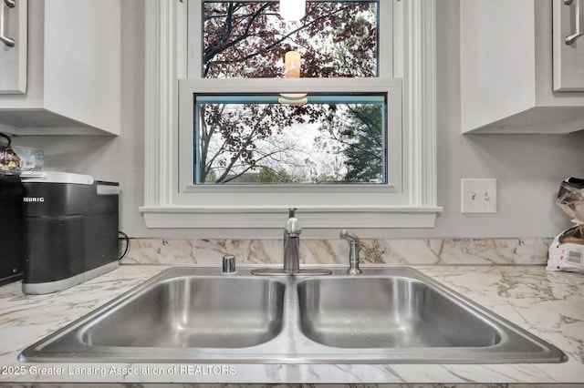 910 Pecos Dr, Lansing, MI 48917 - kitchen view of a sink, white cabinets, and light stone counters