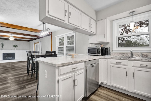 910 Pecos Dr, Lansing, MI 48917 - kitchen with appliances with stainless steel finishes, a sink, healthy amount of natural light, a peninsula, and beamed ceiling