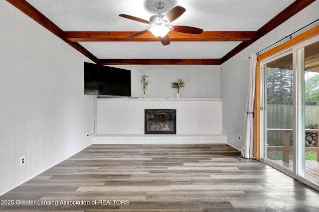 910 Pecos Dr, Lansing, MI 48917 - unfurnished living room with beamed ceiling, healthy amount of natural light, wood finished floors, a brick fireplace, and a ceiling fan