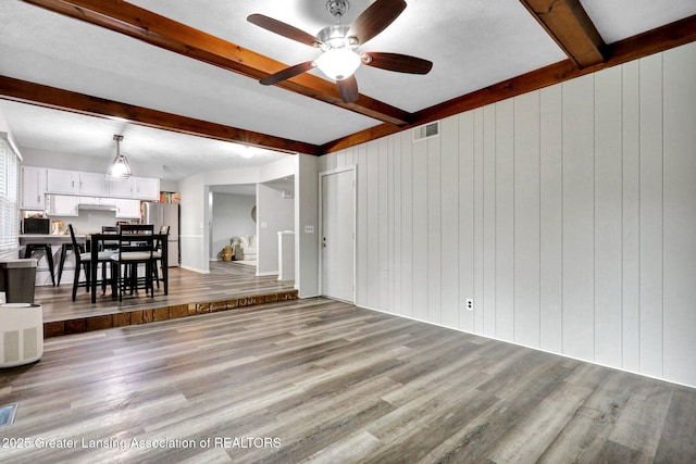 910 Pecos Dr, Lansing, MI 48917 - living area featuring beamed ceiling, wood finished floors, ceiling fan, and wood walls